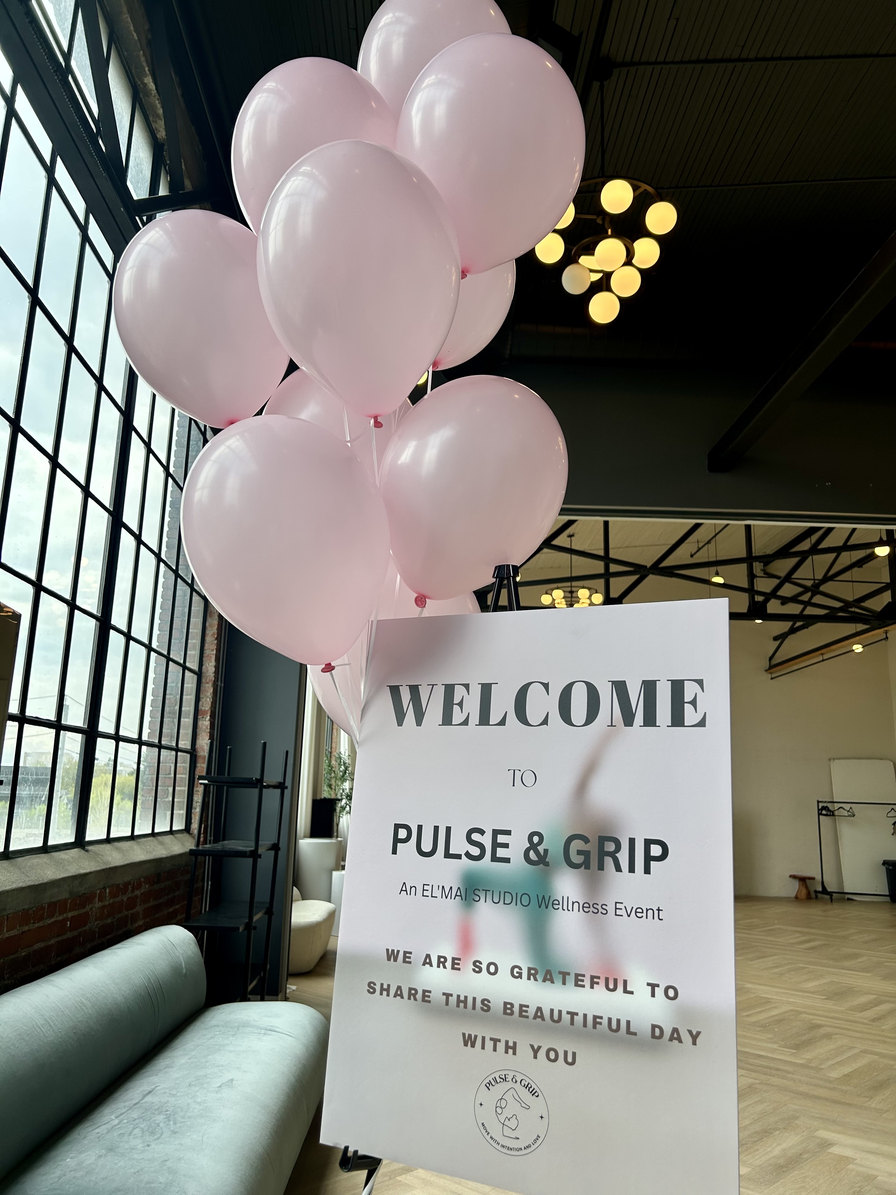 Pink balloons and welcome sign at a Pulse & Grip wellness event